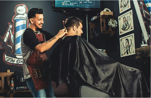 Smiling barber cuts the hair of a man in his barber's chair