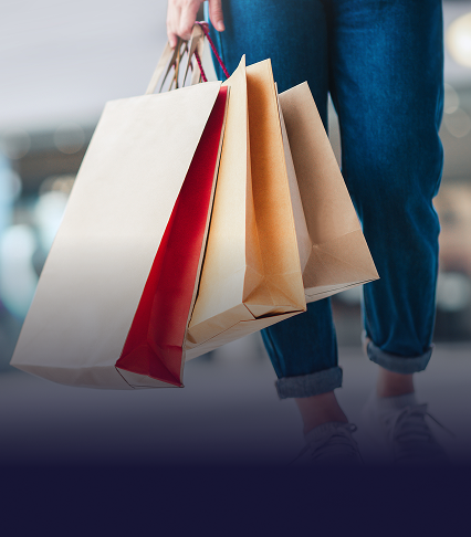 Closeup of various shopping bags being carried by an individual wearing jeans
