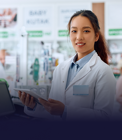A pharmacist standing behind a counter with a tablet in hand